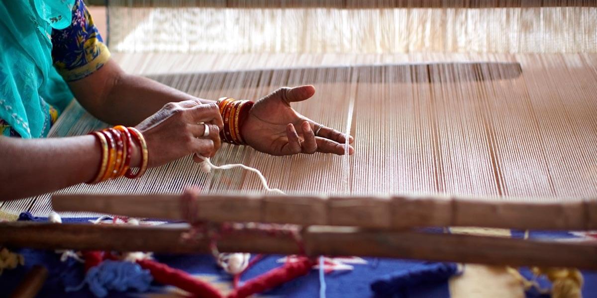 Woman weaving by hand as a result of collaboration with social enterprises 